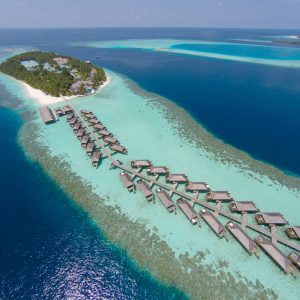 Aerial view of a tropical island in turquoise water. Luxurious over-water villas on tropical island resort maldives for holiday vacation background concept -Boost up color Processing.